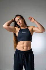 Top deportivo negro con estampado de líneas horizontales y logo de la marca en blanco.
