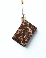 Sobre de mano con estampado animal print en tonos marrón y beige, cierre superior con cremallera y correa de muñeca extraíble.