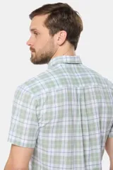 Camisa de manga corta con cuello abotonado y estampado a cuadros en tonos verde claro, blanco y azul. Corte slim fit y bolsillo en el pecho.