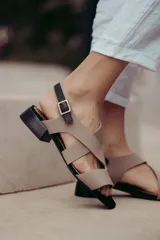 Sandalias de cuero color beige con tiras cruzadas y hebilla lateral. Taco cuadrado color marrón oscuro.