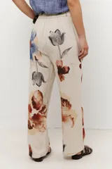 Pantalón de lino color celeste con estampado de flores grandes en tonos marrones, azules y rojos. El pantalón es de corte ancho y tiene cintura alta con cordón ajustable.
