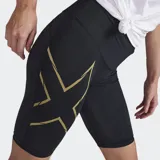 Short de compresión de tiro medio para mujer, color negro, con estampado texturizado y el logo grande de 2XU en amarillo dorado en el muslo izquierdo.