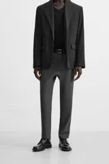 Pantalón slim fit negro confeccionado en tejido con elasticidad en ambas direcciones. Cuenta con bolsillos frontales y traseros de vivo con botón. Cierre frontal con cremallera y botón.