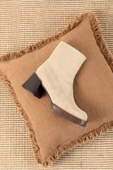 Bota corta de gamuza color beige claro, con caña ajustada y taco cuadrado de madera oscura.