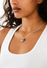 Collar de plata con colgante decorativo de un rostro sonriente y elementos coloridos.