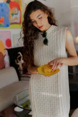 Vestido corto tejido color beige, sin mangas y con cuello redondo.