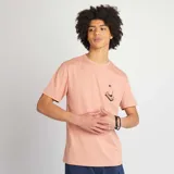 Remera rosa de punto con cuello redondo y estampado de mano sobre un celular.