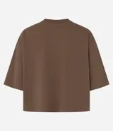 Blusa color beige, cropped y de corte amplio, confeccionada en tejido de media malla, con cuello redondo y mangas cortas.