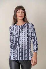 Remera de poliéster y spandex color blanco con diseño gráfico en negro, de manga tres cuartos y cuello redondo.