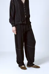 Pantalón negro de corte recto con costuras blancas a contraste.