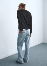 Jeans de mujer color azul claro, de tiro alto, corte wide leg y bajo deshilachado. Cierre de cremallera y botón, con cinco bolsillos y trabillas.