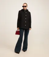 Saco gris de polivelour con capucha, cuello alto con cremallera, abotonado delantero cruzado, bolsillos delanteros y mangas largas.