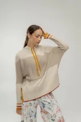 Canguro de punto color crudo y beige con capucha y cordones color mostaza.