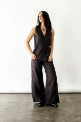 Blusa negra cruzada con lazo lateral, sin mangas y costuras blancas en contraste.