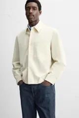Sobrecamisa color crudo de corte regular fit, confeccionada en tejido con mezcla de viscosa. Tiene cuello solapa, manga larga con puños abotonados, bolsillo de parche en el pecho, bajo ajustable con cordones y cierre frontal con botones.