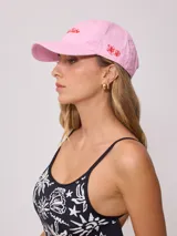 Gorra de lona color crema con visera celeste y bordado frontal con el logo de la marca Rusty en celeste.