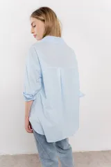 Camisa celeste de algodón con bordado calado tipo broderie, manga larga con puño angosto y botones al frente.