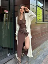 Maxi camisa color crema, con cuello en V, mangas largas con volados y cinturón marrón con tachas.