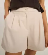 Short gris de sastrería con pliegues delanteros, trabillas en la cintura, bolsillos laterales tipo cuchillo y bolsillos embutidos en la parte trasera.