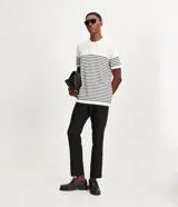 Polo de hombre con corte comfort, confeccionada en tejido de punto de algodón a rayas horizontales blancas y negras. Tiene cuello inglés con botones y mangas cortas.