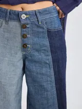 Pantalón ancho de denim con diseño patchwork en diferentes tonos de azul, con tiro alto, corte holgado y cierre frontal con botones.