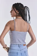Musculosa corta gris de morley con breteles finos y terminación ondulada en el ruedo.
