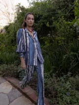 Conjunto estampado con hojas abstractas en tonos marrón y rosa, compuesto por una camisa de manga larga con puños anchos y un pantalón de corte recto.