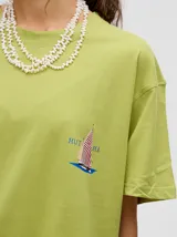 Remera amarilla de corte cuadrado y holgado, con estampado de estrella plateada con borde negro en el frente.