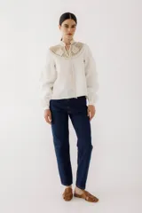 Blusa color ladrillo con cuello alto de crochet y lazos para ajustar. Mangas largas abullonadas con puños elásticos.