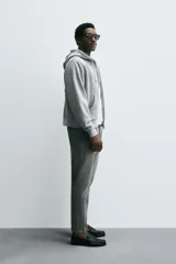 Jeans de denim de algodón, color negro lavado, con tiro medio, corte ajustado en cadera y muslos, y pierna que se estrecha hacia el tobillo. Presenta cinco bolsillos y cierre frontal con cremallera y botón.