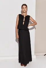 Conjunto de top y falda color crema, confeccionado en lino. El top es sin mangas, con detalle de lazos en el escote y volados en el ruedo. La falda es larga y de corte recto.