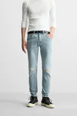 Pantalón de jean negro con corte skinny fit, cinco bolsillos, lavado con efecto roto y cierre frontal con cremallera y botón.