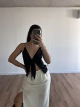 Conjunto de top negro con tirantes finos y falda larga blanca con tajo lateral.