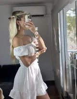 Vestido corto blanco con escote off-shoulder, mangas cortas abullonadas y cintura elastizada.