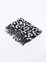 Bufanda rectangular negra con estampado de manchas blancas y flecos en los extremos.