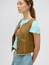 Chaleco de denim liviano color marrón con apliques metálicos y flecos en el ruedo.