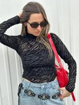 Body negro con estampado animal print de cebra, cuello alto y mangas largas de tul.