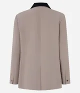 Blazer de tejido plano color beige con estructura de sastrería, cuello smoking con contraste negro en la nuca, botón único para cierre y solapas delanteras que simulan bolsillos.