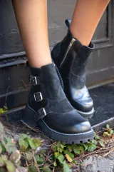 Botas de cuero negro con detalles de hebillas y suela gruesa.
