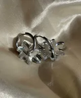 Aros plateados tipo argolla con dije colgante de flor de acrílico transparente.