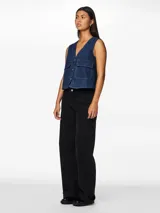 Chaleco denim azul oscuro, con cuello en V, cierre frontal con botones y bolsillos de parche.