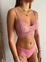 Conjunto de ropa interior color rosado, compuesto por un bralette de encaje con breteles regulables y una bombacha clásica de algodón.