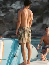 Short de baño blanco con estampado de hojas de palmera en tonos verde, rojo y amarillo.