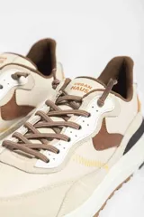 Zapatillas deportivas color beige con detalles en marrón y amarillo.