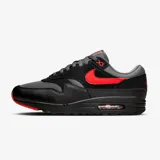 Zapatillas Nike Air Max 1 Essential, con capellada de cuero y tela negra, detalles en gris y logo rojo.