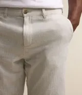 Bermuda de hombre en lino color gris claro, de corte recto, con textura discreta, bolsillos laterales y cierre frontal con botón y cremallera.