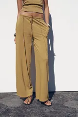 Pantalón ocre de algodón compacto, tiro medio, cintura elástica con cordón ajustable, pierna ancha y efecto lavado.