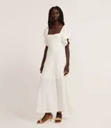 Vestido largo blanco de tejido laise con textura plisada vertical, escote cuadrado y mangas cortas con volado.