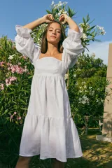 Vestido corto blanco de lino, con escote recto, mangas abullonadas 3/4 con elástico y falda con volado.