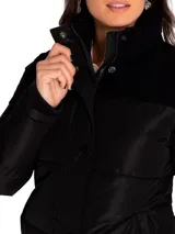 Campera puffer negra para mujer, marca Caterpillar. Cuenta con cuello alto, cierre frontal con botones a presión, bolsillos laterales inferiores, puños y cintura acanalados. Tiene un parche con el logo de Cat en la manga izquierda y forro estampado con el logo de Caterpillar.